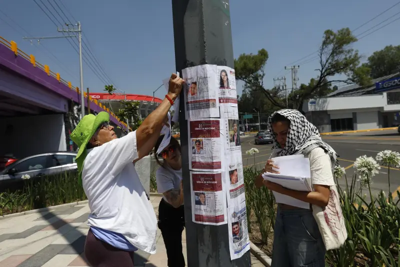 Familias de personas desaparecidas pegan fichas de búsqueda en el Estadio CDMX