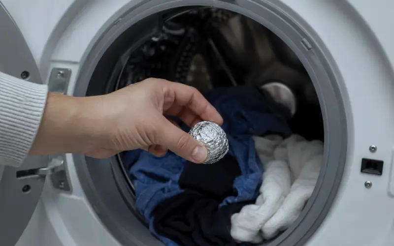 Poner bolas de papel aluminio en la lavadora y secadora en pleno ciclo reduce pelusas y descargas, ya que el metal conduce parte de la carga acumulada en la ropa